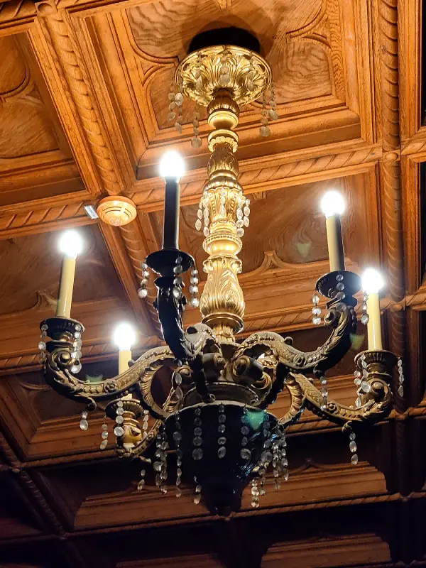 A carved candle chandelier beneath a wooden coffered ceiling