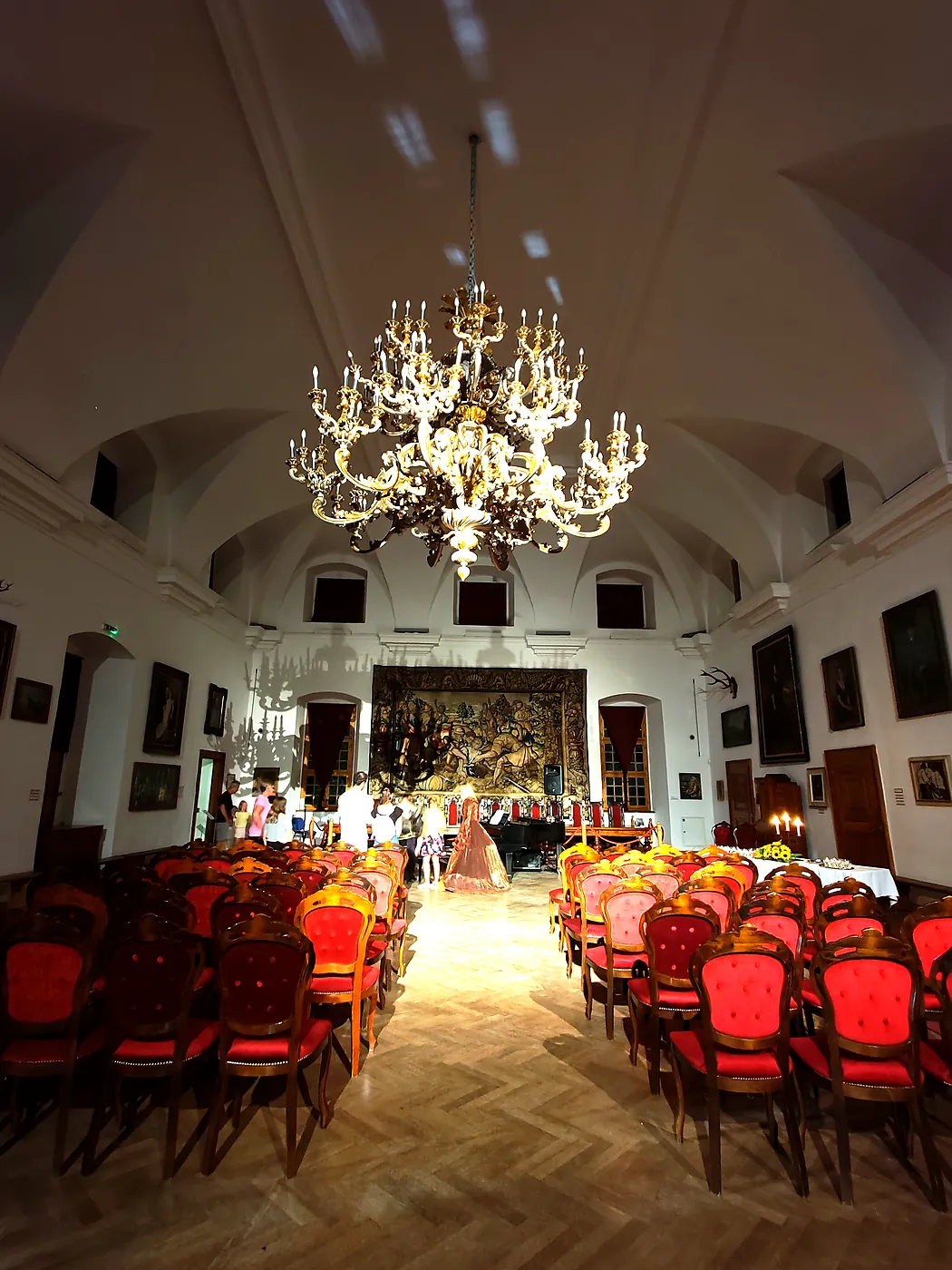 A castle hall with a large chandelier set up for an evening concert